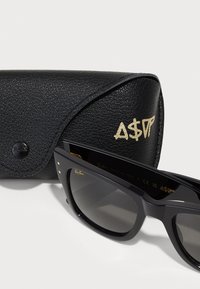 Ochelari de soare negri Ray-Ban cu rame unghiulare, lentile gri, accente aurii și o husă din piele neagră cu litere aurii embossate.