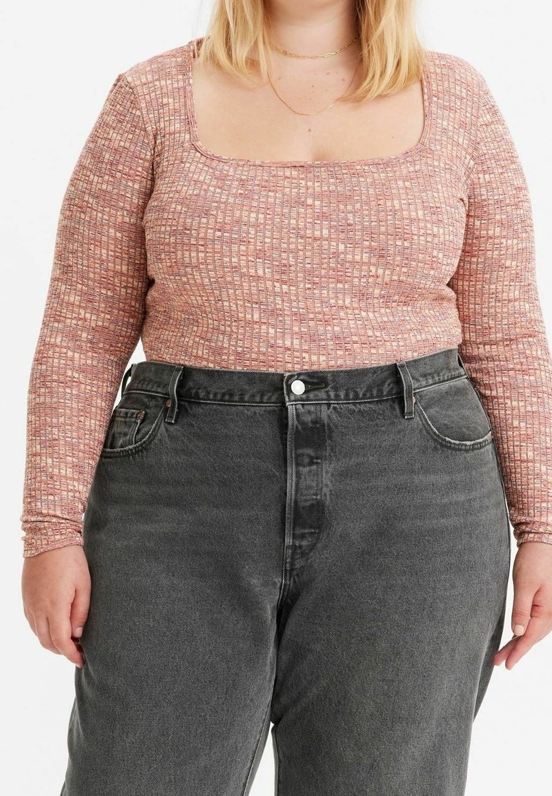 Pitkähihainen, neliönmallinen paita, joka on valmistettu tunnelmallisesta vaaleanpunaisesta ja kermavaisesta kankaasta, yhdistettynä korkeavyötäröisiin tummanharmaisiin farkkuihin, joissa on etupainikkeet ja taskut.