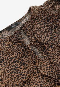 Top s leopardím vzorem v hnědé a černé barvě; má kulatý výstřih, detaily se šňůrkou a texturovaný povrch. Značka: NEXT.