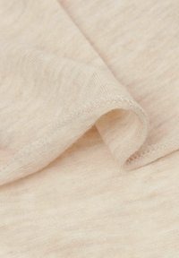 Helles Beige, weicher Stoff mit subtiler Textur, der zarte Nähte entlang der Ränder und einen leichten Glanz aufweist.