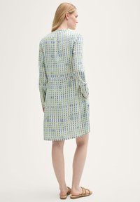 Leichtes, kariertes Kleid in Grüntönen und Blau mit langen Ärmeln, Taillenzug und seitlichen Taschen. Glatter, gemusterter Stoff.