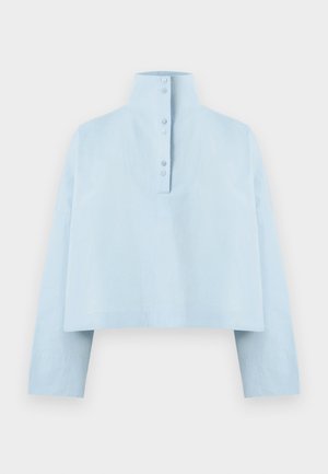 Light blue cropped shirt with a high collar, long sleeves, and five-button closure at the back. Made from a smooth, textured fabric.