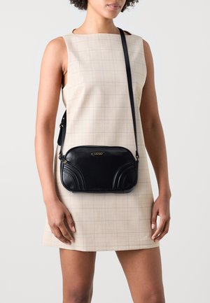 Borsa a tracolla in pelle nera con dettagli curvi, forma rettangolare e logo dorato. Tracolla regolabile e texture liscia.