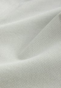 Textil de color gris claro con un sutil patrón geométrico, que presenta pequeños cuadrados en un diseño repetitivo que crea una apariencia texturizada.