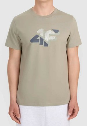 Osoba nosząca beżowy t-shirt z krótkim rękawem z dużym szaro-białym logo "4F" na piersi na jednolitym białym tle.