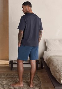 Navy short-sleeve t-shirt paired with blue shorts. T-shirt has a relaxed fit; shorts are straight-cut with side pockets.