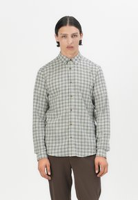 Camisa de hombre de manga larga con botones en un patrón de cuadros verde y beige, con botones marrones y un cuello estándar. Textura de tela suave.