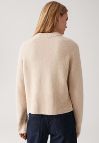 Beige verkürzter Pullover mit weichem, strukturiertem Finish, geripptem Saum und Bündchen, mit Raglanärmeln und minimalistischem Design.