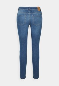 Vaqueros pitillo en denim azul medio con una textura suave. Presentan dos bolsillos traseros, una etiqueta de cuero en la cintura y un corte recto.