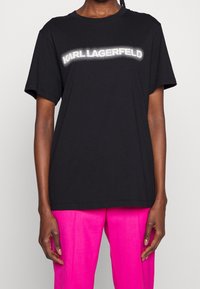 Camiseta de algodón negra de manga corta, que presenta un diseño de logotipo blanco con puntos en el pecho y un corte relajado.