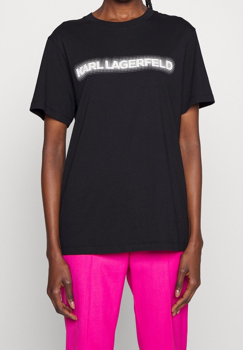 Camiseta de algodón negra de manga corta, que presenta un diseño de logotipo blanco con puntos en el pecho y un corte relajado.