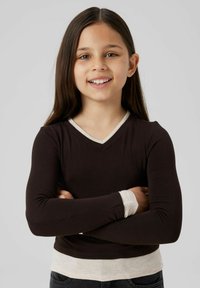 Halenka s dlouhým rukávem, tmavě hnědé barvy, s výstřihem do V a kontrastními světlobéžovými manžetami a lemem. Měkká, pružná tkanina s přiléhavým střihem.