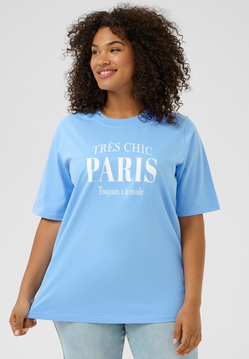 Camiseta de manga corta azul claro con texto blanco que dice "TRÈS CHIC PARIS" y "Toujours à la mode" en un diseño casual.