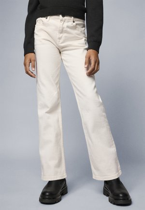 White denim jeans with a straight leg design, featuring front pockets, a button fly, and contrasting stitching, paired with black ankle boots.