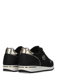 Baskets noires avec un tissu texturé, accents métalliques dorés sur le talon, semelle intermédiaire blanche et un logo circulaire sur le côté.
