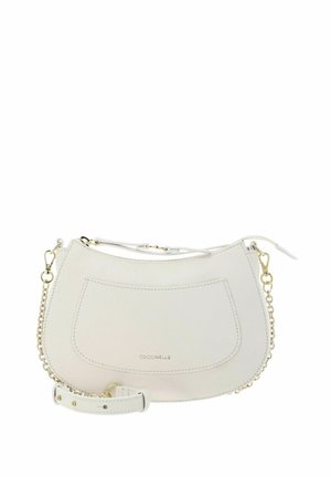 Sac à bandoulière en cuir crème avec poche avant, bandoulière chaîne dorée et fermeture éclair, marqué "Coccinelle" sur la poche.