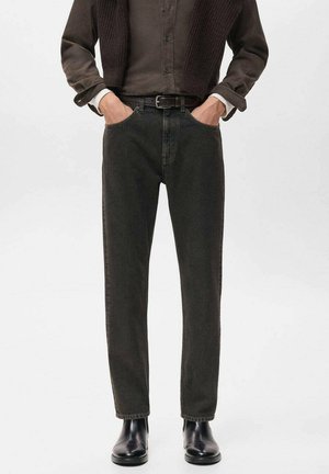 Jeans verde oscuro con un diseño de pierna recta, hechos de denim. Presentan bolsillos laterales y un cinturón, combinados con botas negras hasta el tobillo.