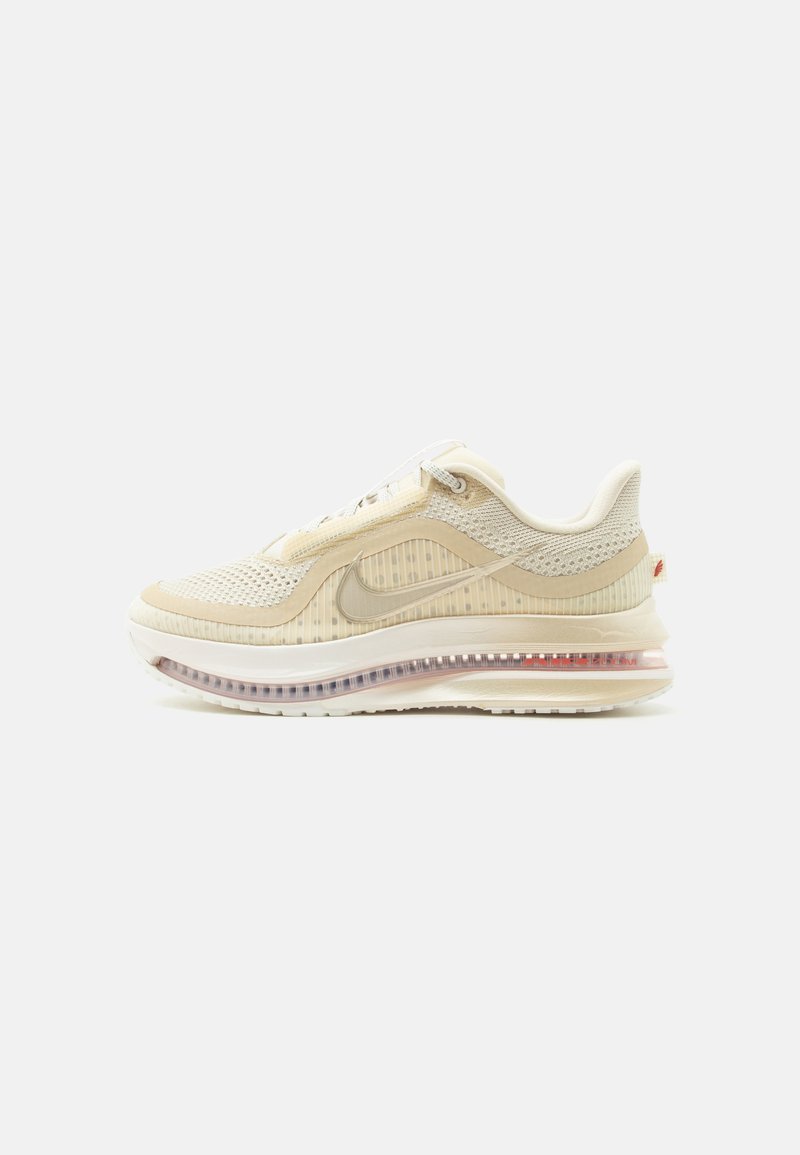 Μπεζ και κρεμ αθλητικό παπούτσι Nike με επάνω μέρος από δίχτυ, ορατή σόλα με αεριζόμενο μαξιλάρι και διακριτικό λογότυπο Swoosh στο πλάι, εμφανίζεται σε πλάγια όψη.