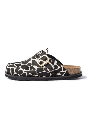 Sabot à enfiler avec imprimé animal noir et blanc, bride à boucle dorée, semelle intérieure en liège et semelle extérieure en caoutchouc noir sur fond blanc.