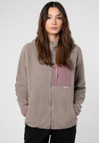Grijze fleecejack met een ritssluiting aan de voorkant, een mauve borstzak en elastische manchetten. Kenmerkt zich door een merklabel op de zak en een zachte textuur.