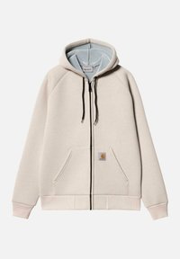 Sudadera con cremallera de color beige claro, hecha de un tejido suave, con un forro interior azul, bolsillos tipo canguro y un parche con el logo en la parte frontal. Cuerdas de ajuste negras.