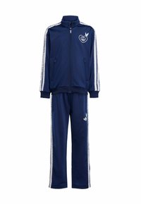 Námořnický modrý teplákový komplet s bílými bočními pruhy, bunda na zip s logem srdce a holubice, odpovídající kalhoty s logem na stehně.