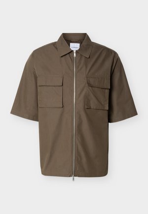 Camicia verde oliva a maniche corte con cerniera frontale e due tasche con patta sul petto, distesa su uno sfondo bianco.