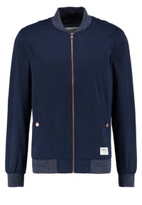 Marineblauw bomberjack gemaakt van gladde stof met een geribde kraag en manchetten. Voorzien van een bronzen rits en twee zijzakken met knoopaccenten.