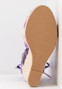 Sandale compensée avec semelle en caoutchouc texturée indiquant la taille 37, lanières en tissu tie-dye violet et talon style espadrille tissé.