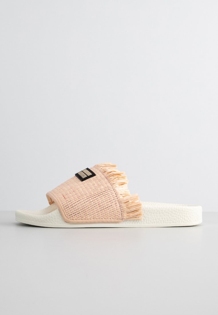 Slide sandal featuring a textured woven upper in light pink with fringed detailing, complemented by a white, cushioned sole.