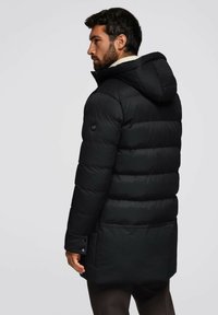 Giacca a vento nera con cappuccio, caratterizzata da un design trapuntato, tasche laterali e dettagli a bottoni sui polsini. Tessuto morbido e liscio.