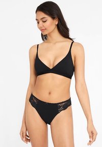 Svart underklädesset med en enkel bralette med tunna band och trosor med spetskant, som visar upp delikata detaljer och mjuk textur.