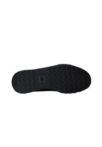 Semelle en caoutchouc noir avec un motif texturé de formes hexagonales et un logo central. Design plat et robuste pour une adhérence optimale.