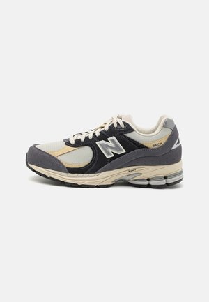 Męskie sneakersy New Balance 2002R w kolorach beżowym, czarnym i szarym, z panelami z siateczki i zamszu, z amortyzowaną podeszwą i sznurowanym zapięciem.