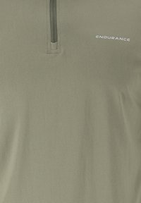 Lyhythihainen oliivinvihreä polo-paita, jossa on puolivetoketju kaula-aukko, teksturoitu kangas ja valkoinen "ENDURANCE" -logo rinnassa.