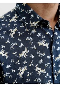 Camicia floreale blu navy con un motivo a piccola scala di fiori e foglie bianchi e beige, con una finitura testurizzata e colletto classico.