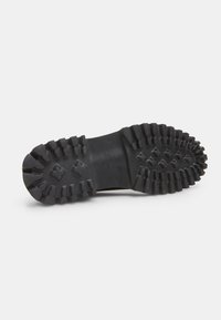 Semelle en caoutchouc noir avec un motif de semelle profonde, présentant une épaisseur variable des crampons pour une traction optimale. La marque est embossée au centre et indique "Bata 31".