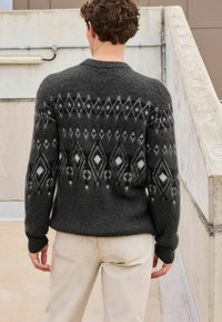 Gray knitted sweater with a geometric pattern, featuring diamond shapes in lighter gray and white. Plain cuffs and hem, soft texture.
