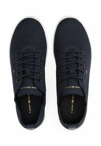Sneakers in tela blu con suole in gomma bianca, punta rotonda e lacci con occhielli. Presentano un piccolo logo sul lato e il testo dorato del marchio all'interno.