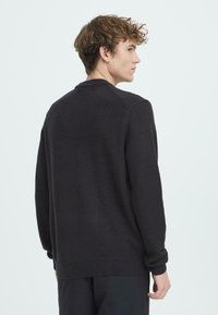 Maglione grigio scuro con scollo rotondo, polsini e orlo a costine. Tessuto morbido e design semplice, visto da dietro.