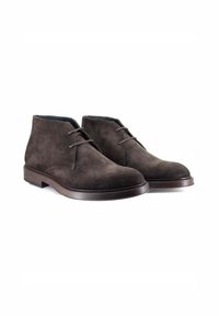Stivali chukka in suede marrone scuro con punta tonda, chiusura con lacci e una suola in gomma marrone scuro liscia. Design minimalista senza motivi visibili.