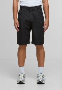 Shorts noirs ajustés avec un design plissé, dotés d'une taille avec une fermeture à bouton. Fabriqués à partir d'un matériau lisse et léger.