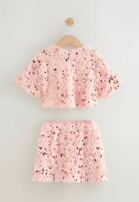 Rosa, kuscheliges Crop-Top und passender Rock, beide mit Pailletten verziert. Weicher Stoff mit Kurzarmdesign und elastischem Bund.
