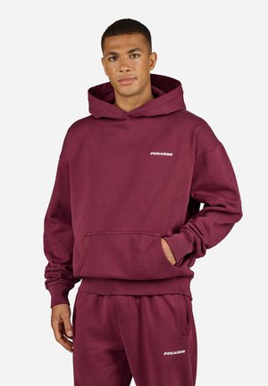 Maroon cotton hoodie with a front pocket and ribbed cuffs, featuring a white "PEGADOR" text logo on the chest.