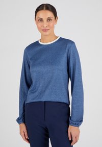 Blauw langemouwen top met een gestructureerde afwerking, ronde halslijn met witte rand, en gathered manchetten, gecombineerd met navy broek.