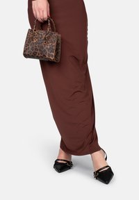 Borsa a tracolla con stampa leopardata, di piccole dimensioni e manici arrotondati; abbinata a un vestito marrone attillato e ballerine nere a punta con cinturino alla caviglia.