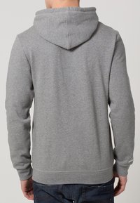 Sudadera con capucha gris, de tejido suave y texturizado, con mangas largas, un bolsillo tipo canguro y puños y dobladillo acanalados.