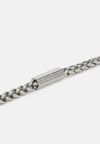 Sølvmetal kædearmbånd med et glat, snoet design og en rektangulær lås, der har en række indfattede klare sten.