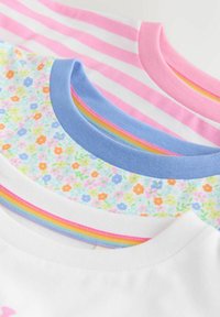 Camisetas infantiles apiladas con rayas rosas/blancas, estampado floral multicolor con cuello azul y blanca con detalles en arcoíris.
