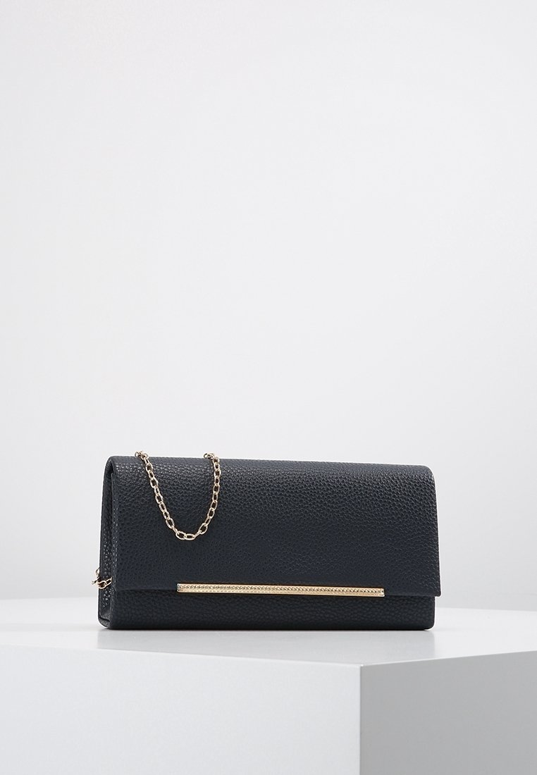 Sac à main noir texturé avec une chaîne dorée et un accent métallique à l'avant, doté d'une fermeture à rabat.